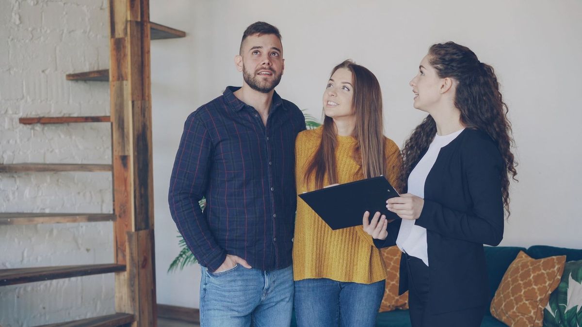 Trois individus en conversation dans un salon avec une échelle en bois et un classeur Trois individus en conversation dans un salon avec une échelle en bois et un classeur