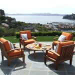 Terrasse avec fauteuils en bois offrant une vue sur la mer et les collines