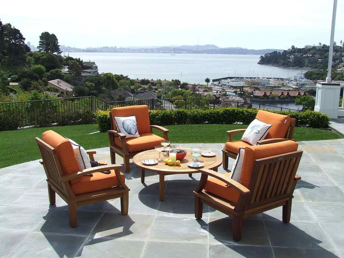 Terrasse avec fauteuils en bois offrant une vue sur la mer et les collines