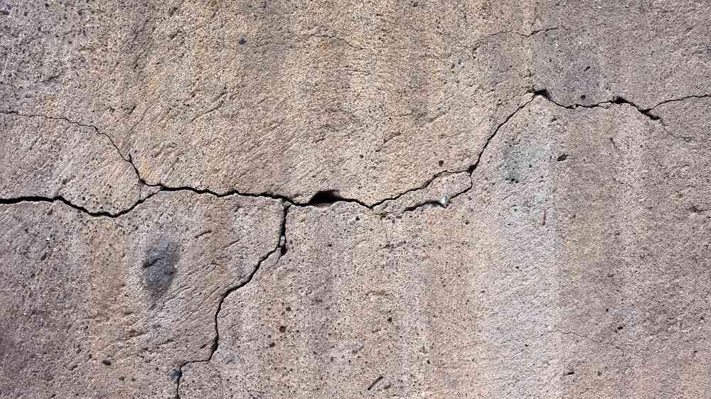 Mur en béton avec fissures profondes et surface rugueuse